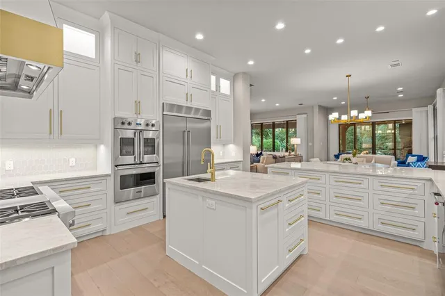 a kitchen with kitchen island granite countertop a sink cabinets and stainless steel appliances