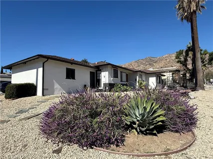 a view of a house with a yard and potted plants