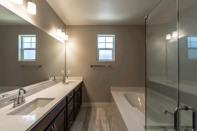 a bathroom with a double vanity sink a toilet and shower