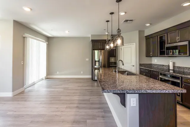 a kitchen with stainless steel appliances granite countertop a sink a stove and a wooden floors