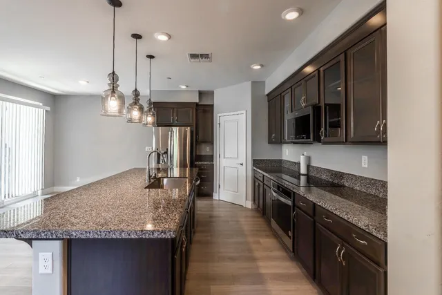 a kitchen with granite countertop kitchen island stainless steel appliances a sink stove and refrigerator
