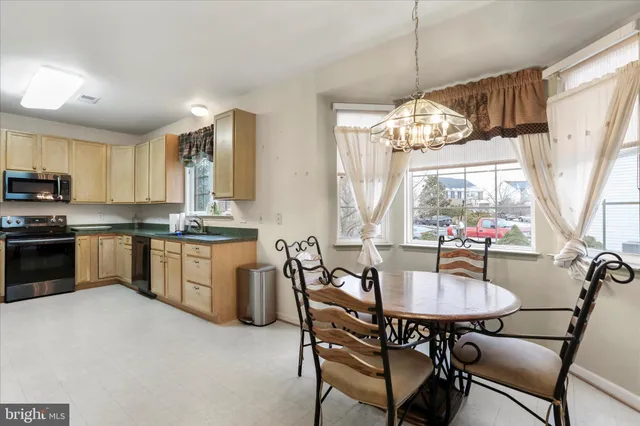 a kitchen with a dining table chairs stainless steel appliances and cabinets