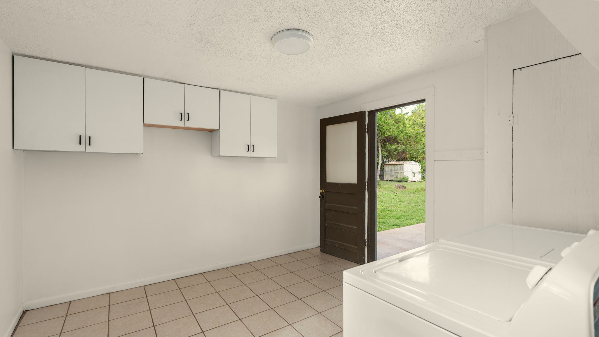 206 East Skyview Road Austin, TX 78752 - Photo 25 of 32 Functional laundry space with ample cabinet storage and convenient outdoor access.