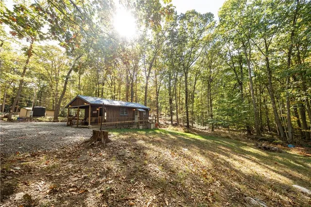 a view of a house with a yard and large trees