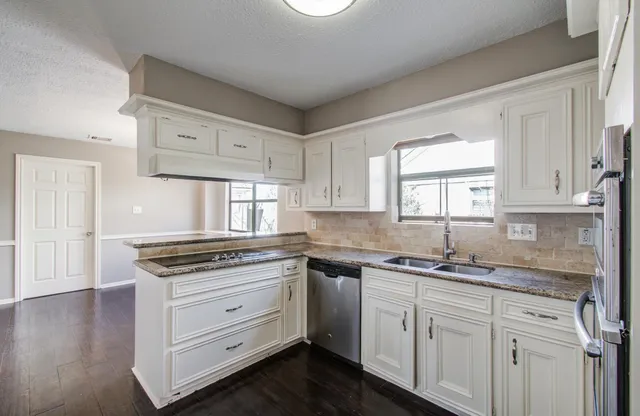 a kitchen with granite countertop white cabinets and white appliances