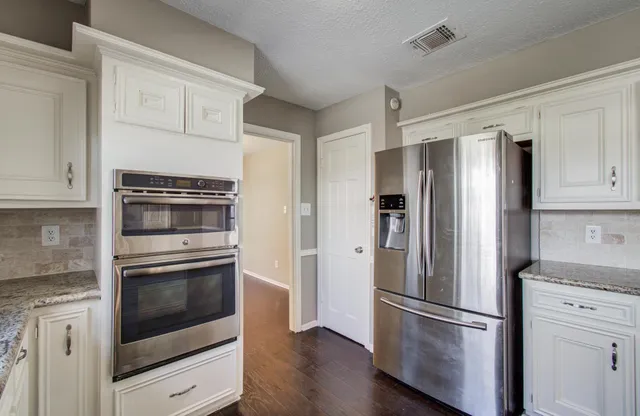 a metallic refrigerator freezer sitting in a kitchen