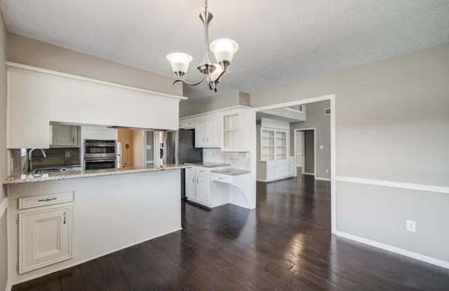 a large kitchen with cabinets wooden floor and stainless steel appliances