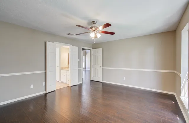 a view of an empty room with a window and a ceiling fan