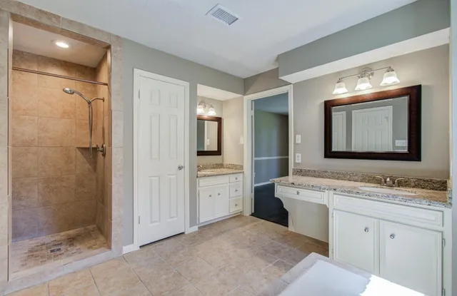 a spacious bathroom with a granite countertop sink mirror and shower