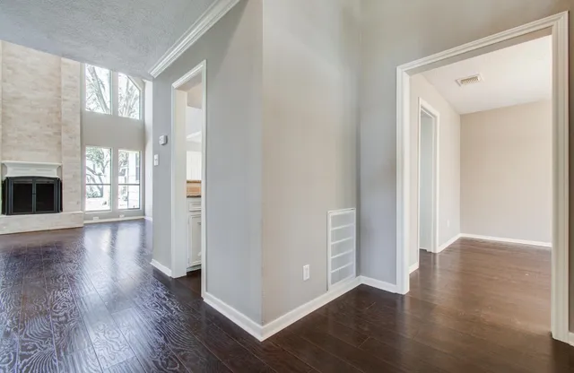 an empty room with wooden floor fireplace and windows