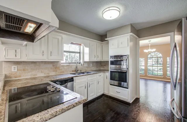 a kitchen with granite countertop white cabinets and stainless steel appliances