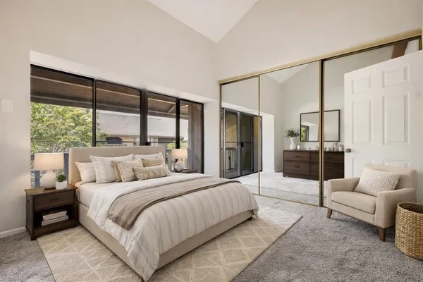a bedroom with a bed couch and large window