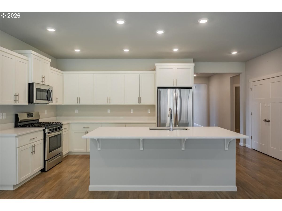 315 Cypress Street Mount Angel, OR 97362 - Photo 11 of 43 a kitchen with stainless steel appliances granite countertop a stove a sink and a refrigerator with wooden floor
