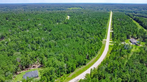an aerial view of residential houses with outdoor space and trees
