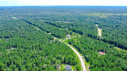 an aerial view of residential house with outdoor space and trees all around