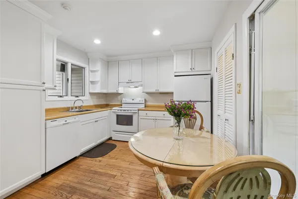 a kitchen with kitchen island a stove a sink a refrigerator and white cabinets with wooden floor