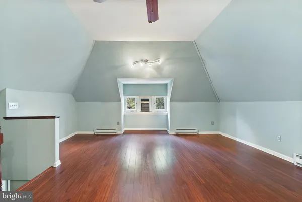 an empty room with wooden floor cabinet and windows