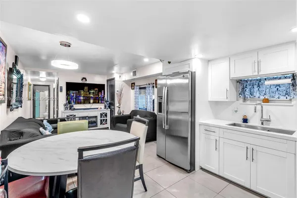 a kitchen with stainless steel appliances kitchen island granite countertop a refrigerator a sink a stove a dining table and chairs