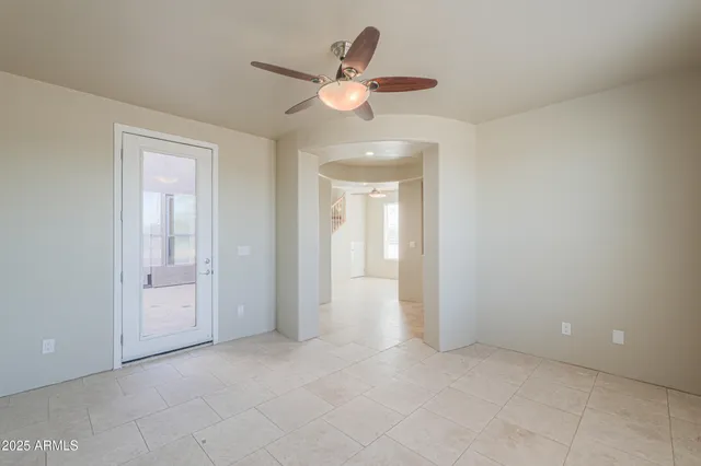 a view of an empty room with wooden floor and a ceiling fan