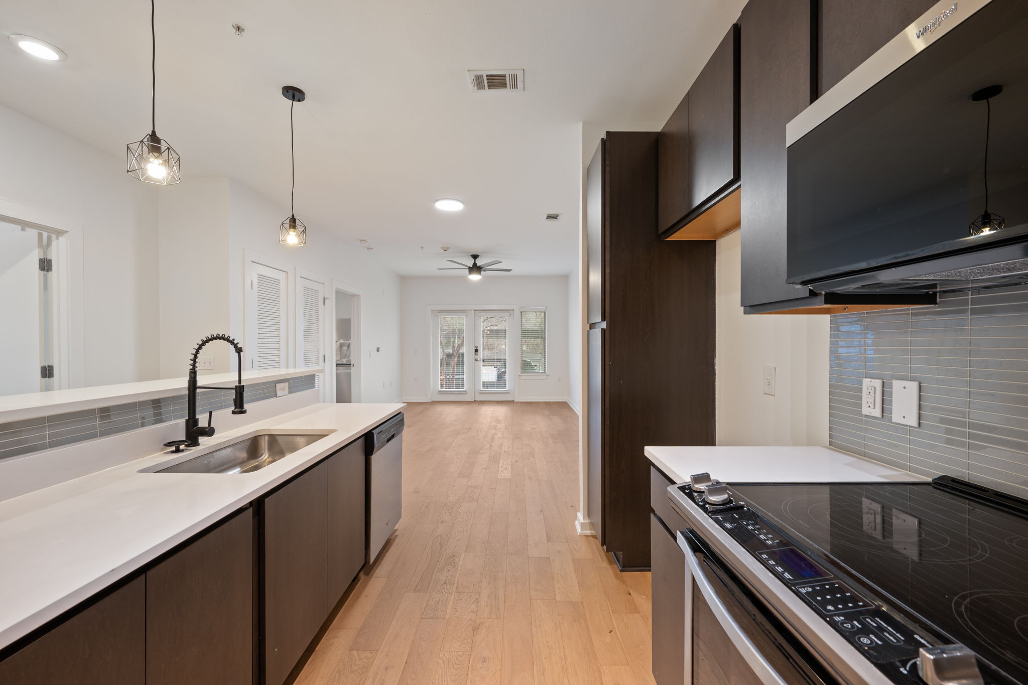 2505 Thornton Road, Unit 3103 Austin, TX 78704 - Photo 1 of 1 Kitchen with backsplash, dark brown cabinets, stainless steel appliances, hanging light fixtures, and recessed lighting