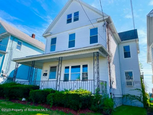 a view of a house with brick walls and a yard with plants
