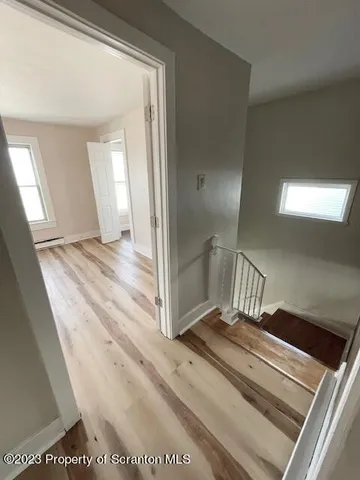 a view of a hallway to a bedroom with wooden floor and windows