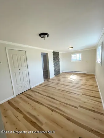 a view of empty room with window and wooden floor