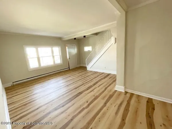a view of an empty room with wooden floor and a window