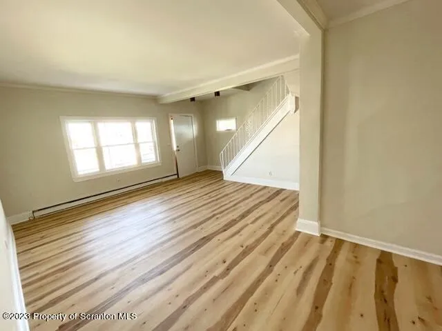 a view of an empty room with wooden floor and a window