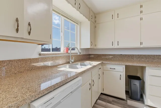 a kitchen with granite countertop white cabinets and a sink