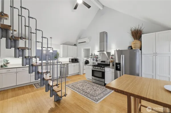 a kitchen with stainless steel appliances kitchen island granite countertop a refrigerator a stove a sink dishwasher and white cabinets with wooden floor