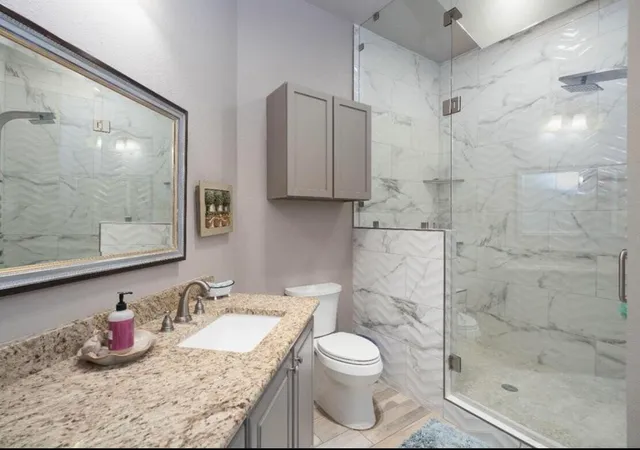 a bathroom with a granite countertop sink toilet and shower