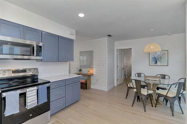 a kitchen with stainless steel appliances a stove a sink a microwave a refrigerator and chairs