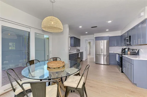 a kitchen with stainless steel appliances granite countertop a sink a stove a refrigerator cabinets a dining table and chairs