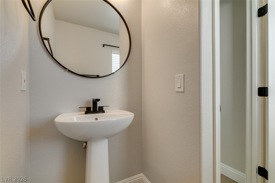8909 Houston Ridge Avenue Las Vegas, NV 89178 - Photo 25 of 45 A sleek pedestal sink with a modern faucet provides both style and utility in this well-appointed bathroom.