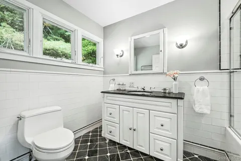 a bathroom with a granite countertop toilet a sink and a mirror