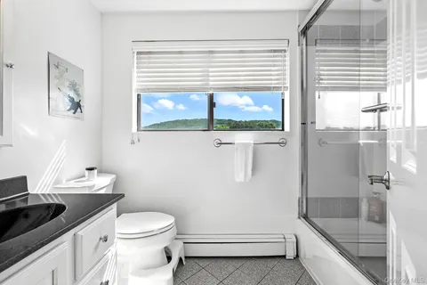 a bathroom with a granite countertop toilet a sink and a window