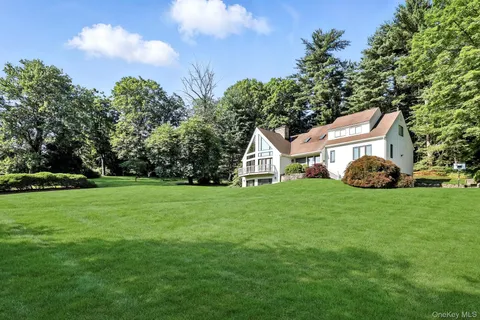 a view of a white house in front of a big yard with large trees