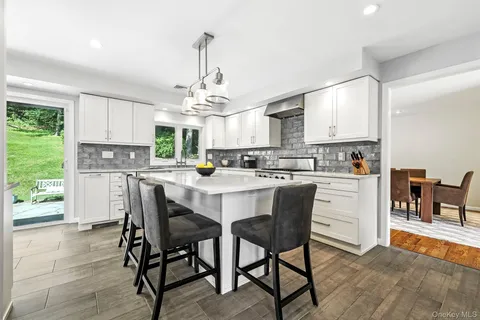 a kitchen with stainless steel appliances kitchen island a table chairs and a refrigerator