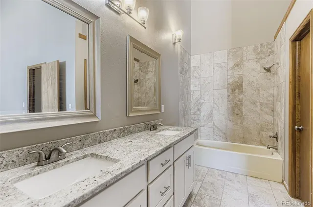a bathroom with a granite countertop sink mirror and a bath tub