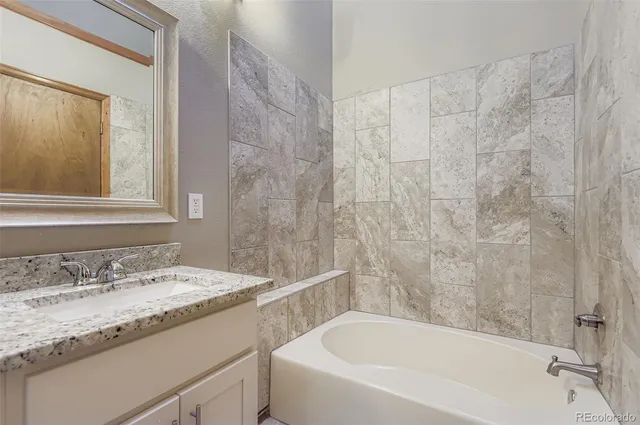 a bathroom with a granite countertop sink and a bathtub