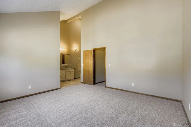 a view of an empty room with closet and a bathroom