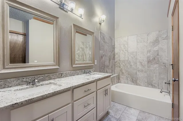 a bathroom with a granite countertop sink a mirror a bathtub and next to a window