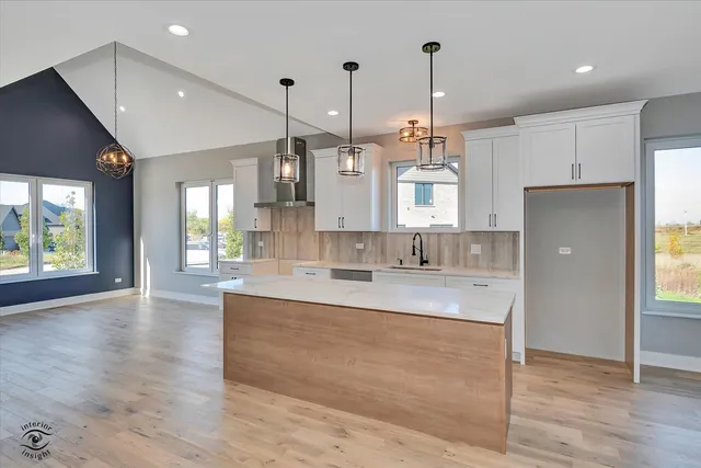 a large kitchen with granite countertop a large kitchen island a sink dishwasher a refrigerator and wooden floor