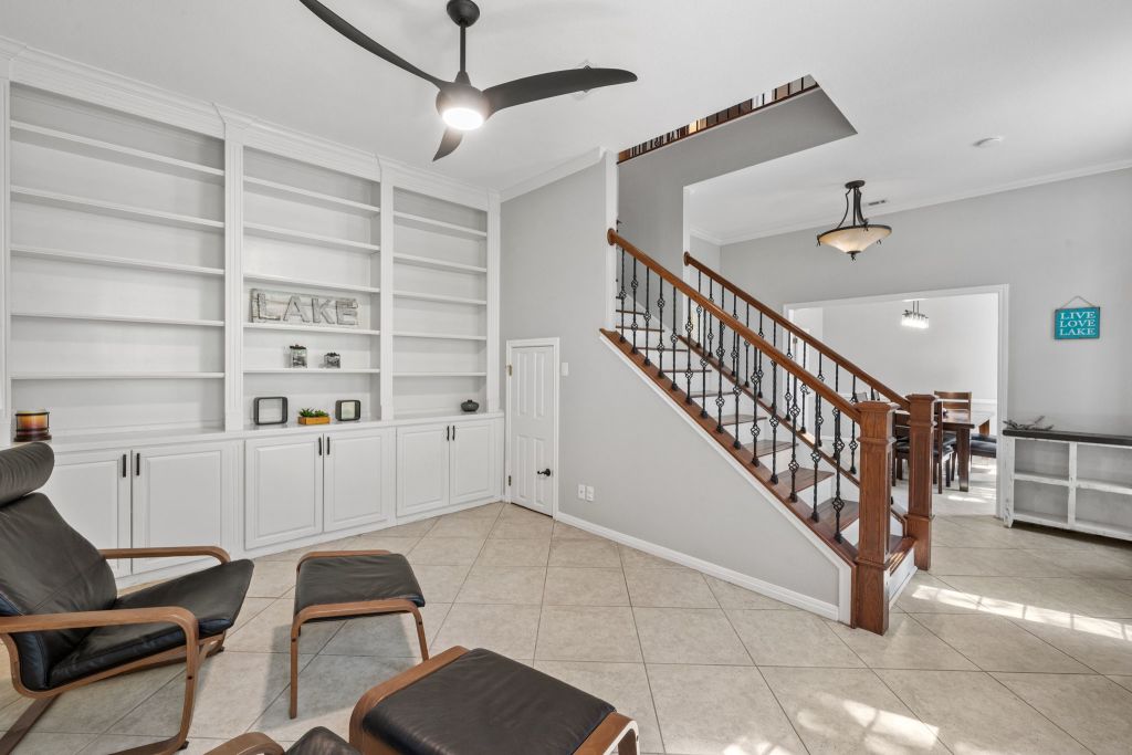 10800 Beach Road Leander, TX 78641 - Photo 9 of 39 Built-in shelving and a striking staircase with intricate balusters define this inviting living space.