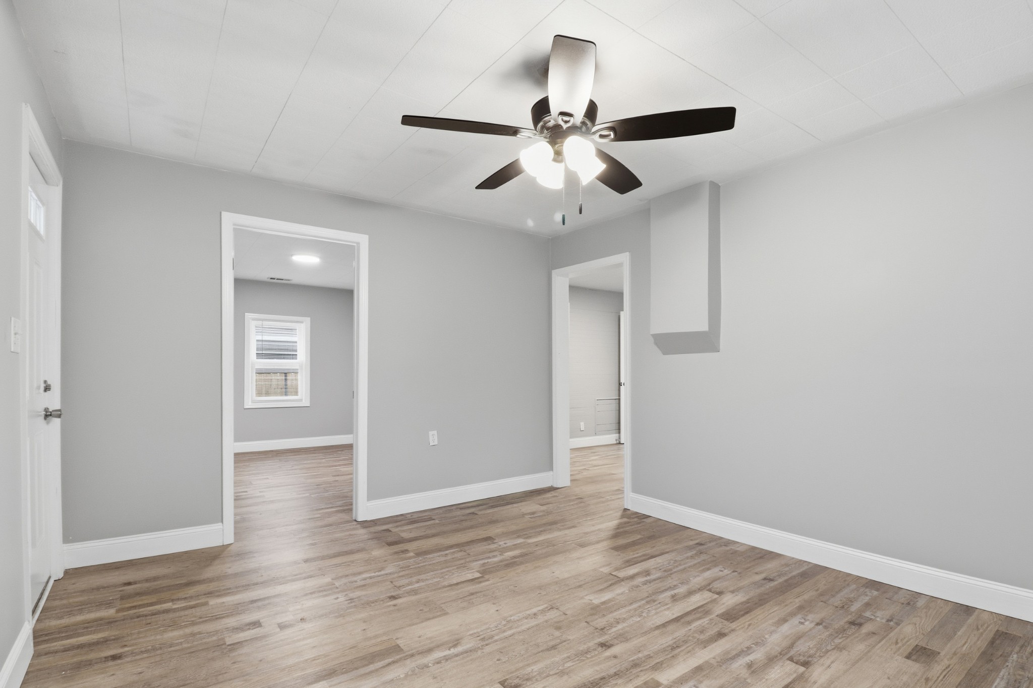 612 Maple Street Manchester, TN 37355 - Photo 7 of 20 an empty room with wooden floor ceiling fan and windows