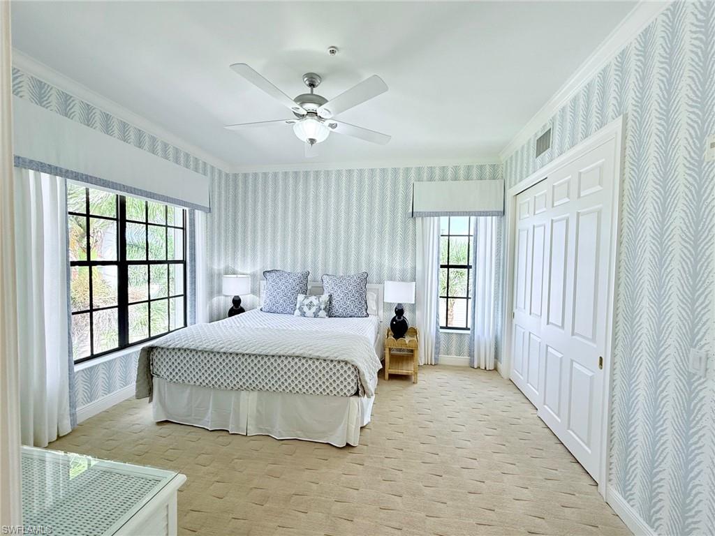 705 10th Street South, Unit 301 Naples, FL 34102 - Photo 22 of 35 a bedroom with a large bed and a chandelier