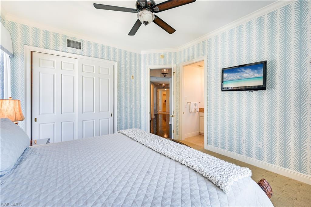 705 10th Street South, Unit 301 Naples, FL 34102 - Photo 23 of 35 a bedroom with a bed and a chandelier