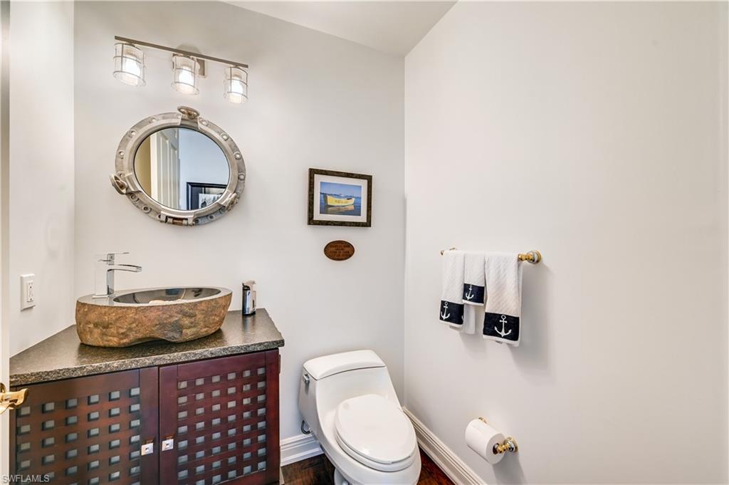 705 10th Street South, Unit 301 Naples, FL 34102 - Photo 28 of 35 a bathroom with a toilet a sink and mirror