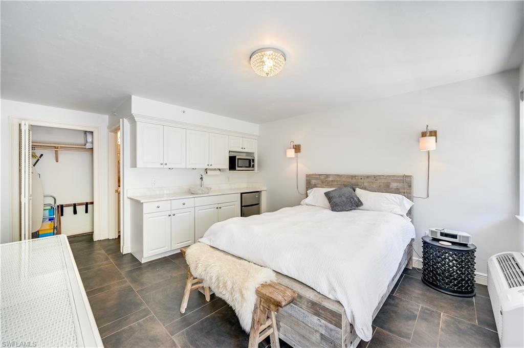 705 10th Street South, Unit 301 Naples, FL 34102 - Photo 32 of 35 a bedroom with a bed and a chandelier